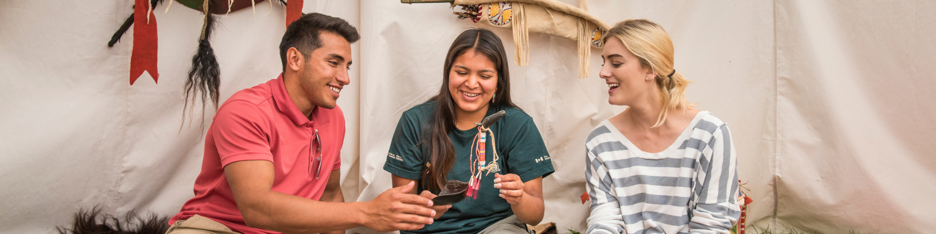 A Parks Canada interpreter shows visitors Indigenous artifacts as part of the Anishinabe cultural workshop program