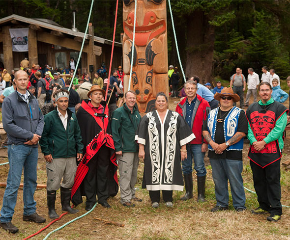 Haida president Peter Lantin (third from left) and Parks Canada CEO Alan Latourelle (fourth from left) are flanked by the Archipelago Management Board members who are standing in front of the pole they commissioned to celebrate 20 years of cooperative management in Gwaii Haanas