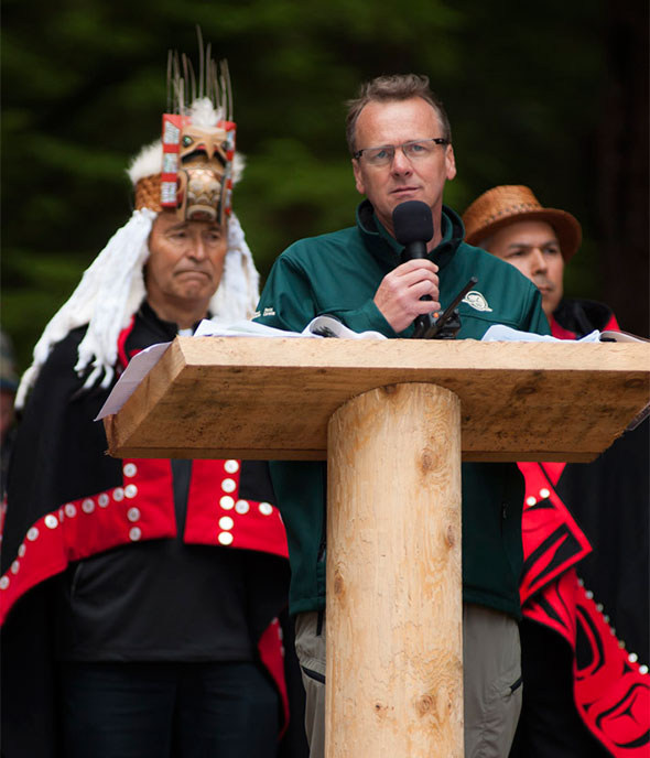 Le directeur général de Parcs Canada Alan Latourelle, accompagné du chef héréditaire Gidkun Reg Young (à gauche) et du président haïda Peter Lantin (à droite), s’adresse à la foule