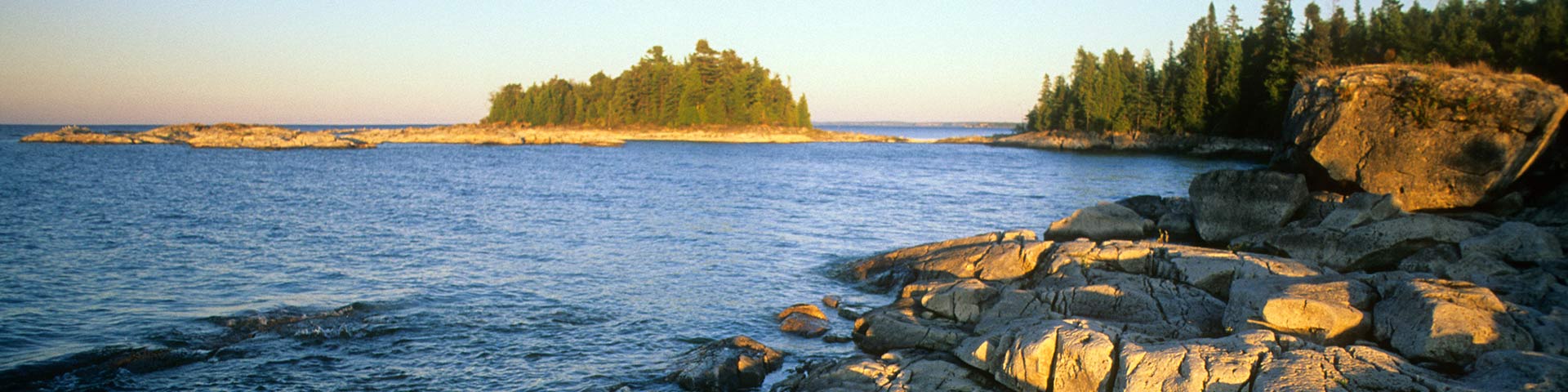 A rocky shoreline with islands in the distance.