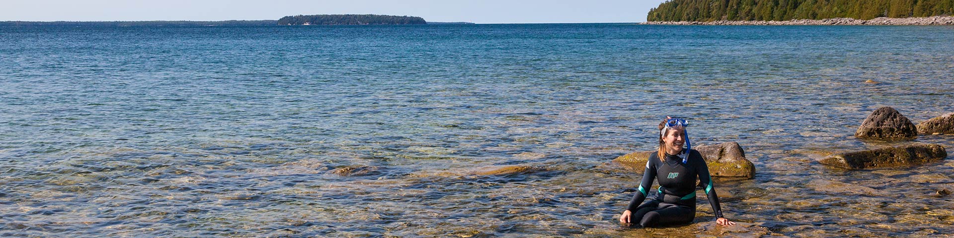 Snorkeler diver along a rocky shoreline.