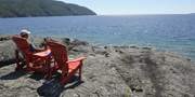 A person sitting in a red chair, overlooking Lake Superior