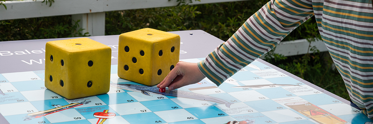 Deux gros dés jaunes posés sur une planche de jeu de société.
