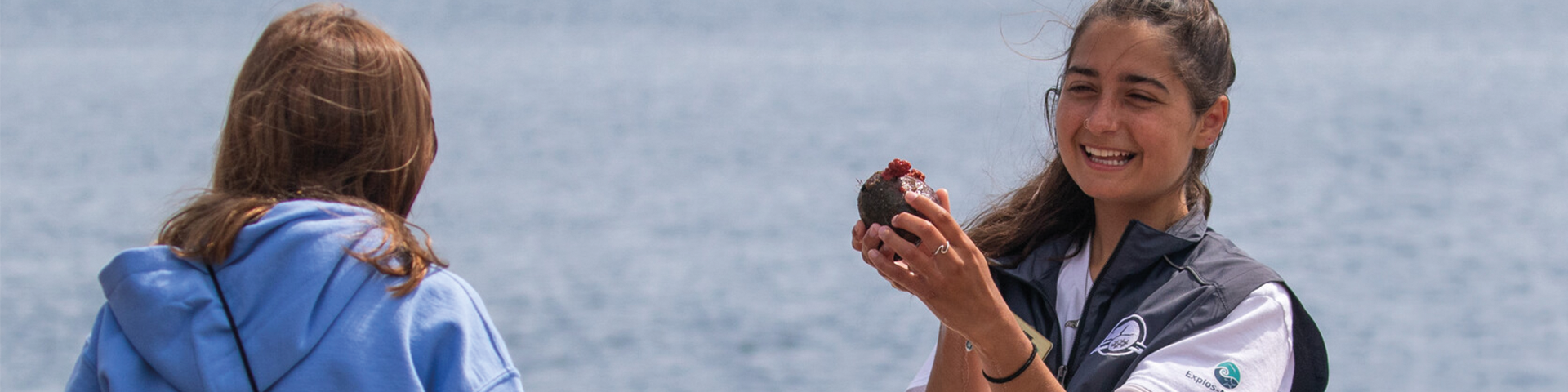 A guide-interpreter smiles as she holds up a coral.