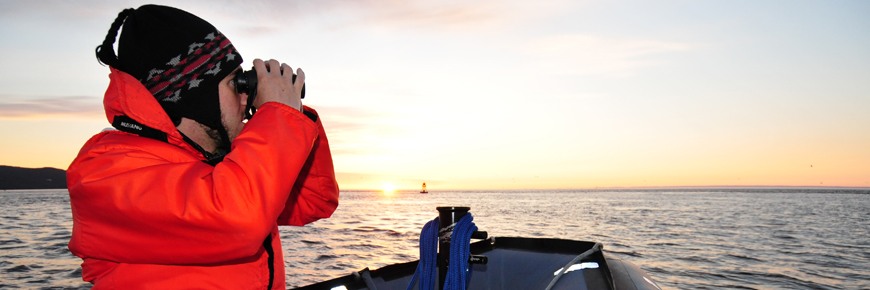 A visitor on an inflatable boat scans the sea with binoculars.