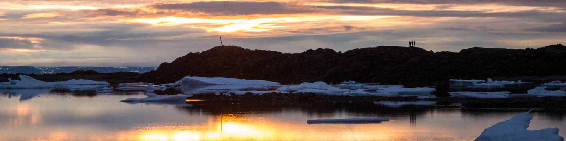 Quatre personnes sur un rivage au coucher du soleil.