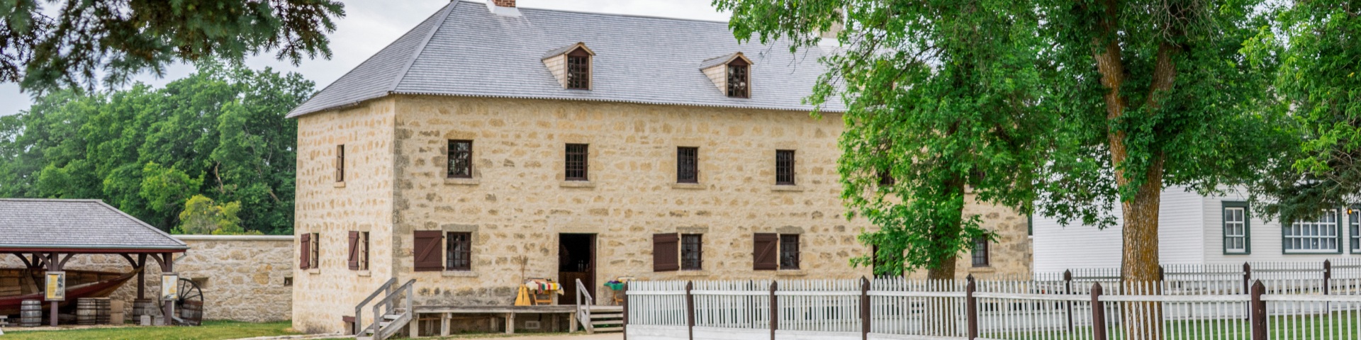 Grand bâtiment en pierre coiffé d'un toit à pente moyenne, percé de lucarnes à pignon et doté de deux cheminées en pierre.