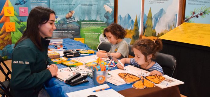 A Parks Canada heritage presenter assists children with art & crafts.