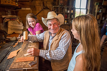 An interpreter shows two girls how to make crafts in the leather shop