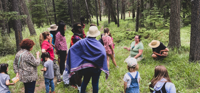 A group of people in the forest listening to a Métis guide during a plant identification walk