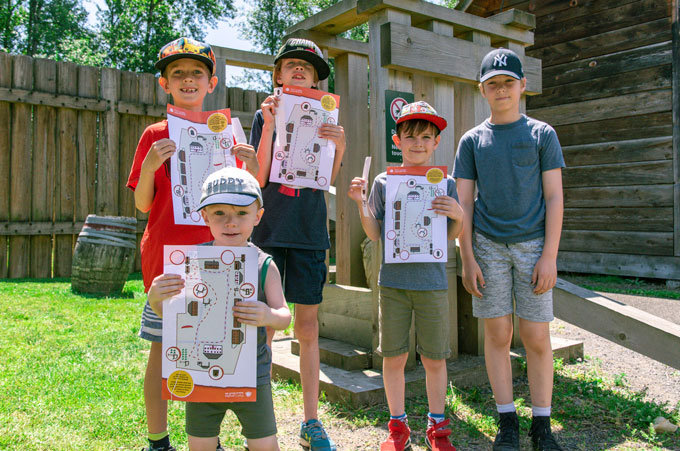 Cinq enfants posant avec une feuille d'activité du lieu historique national du Fort-Langley.