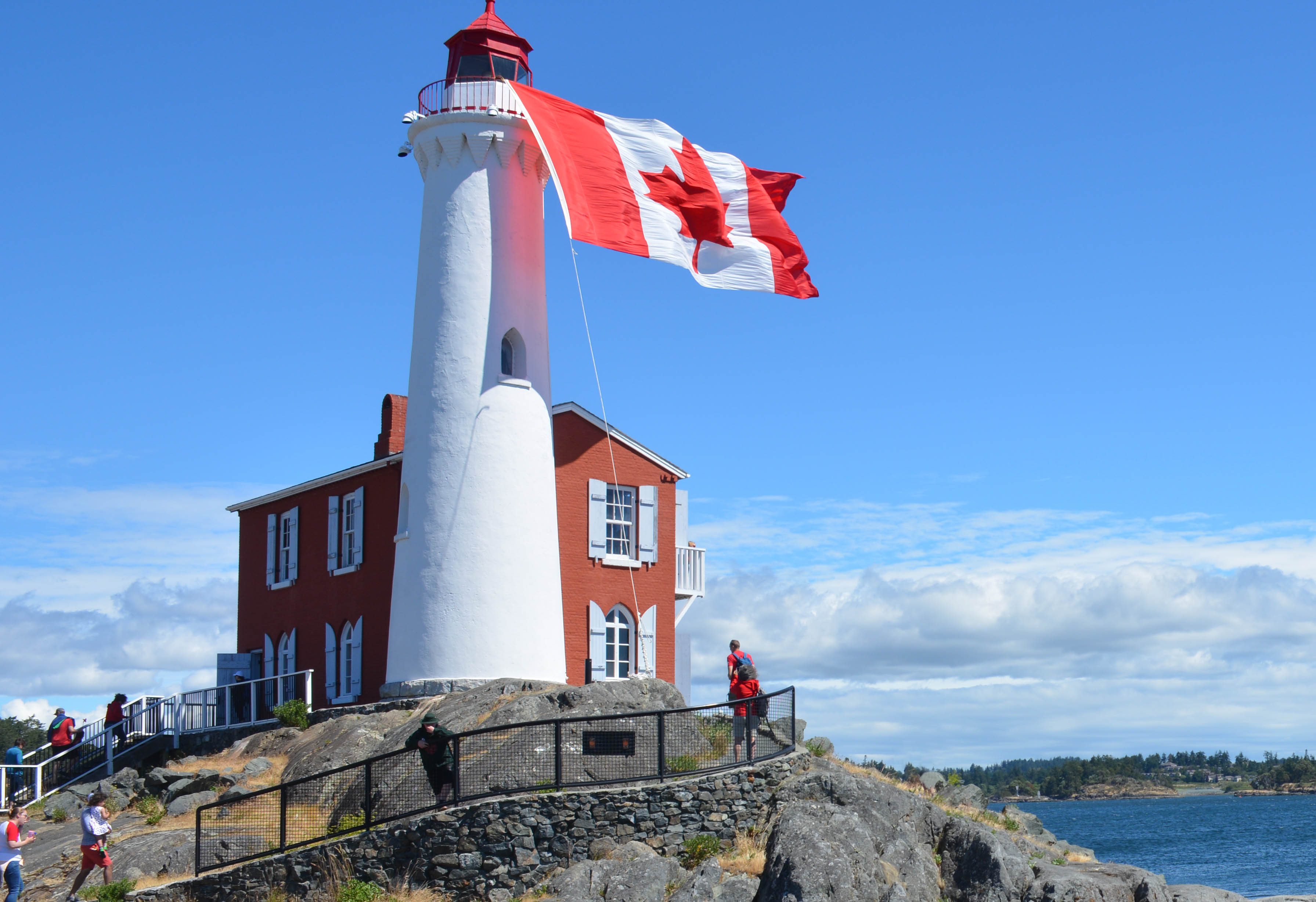 A giant Canada flag hanging from the top of the Fisgard lighthouse tower flying in the wind.