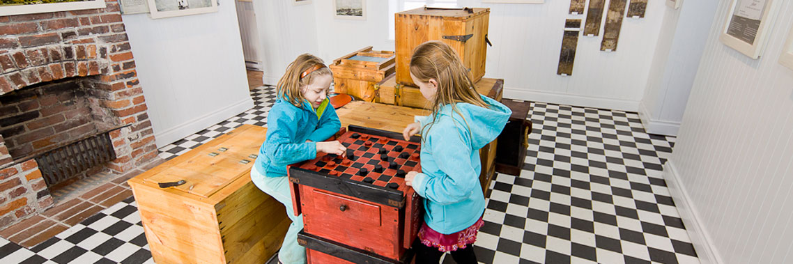 Deux enfants jouent à un jeu de dames à disposition dans l'exposition interactive du phare.