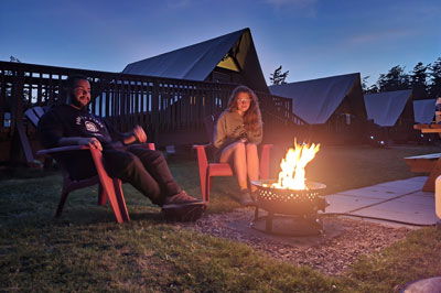 Au coucher du soleil, un couple se détend près d’un foyer au propane.