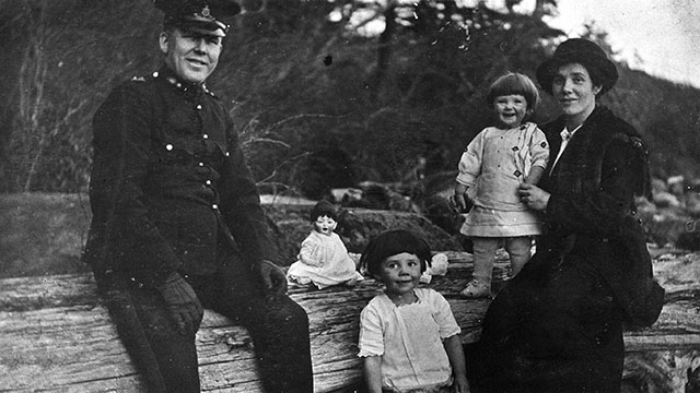 An officer in uniform poses with his wife and two little girls and their doll, circa 1914.