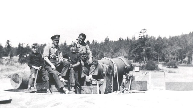 A couple of officers and kids sit on a canon, circa 1932.