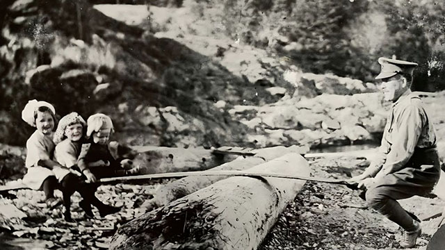 A soldier in uniform plays on a teeter-totter made with beach wood with his children, circa 1916. 