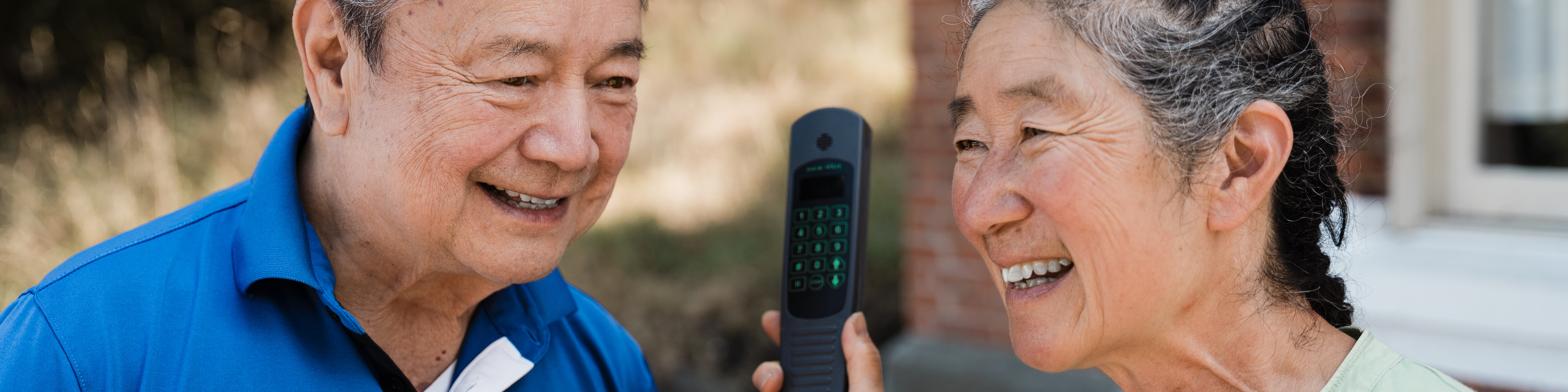 A couple holding an electronic device and smiling.