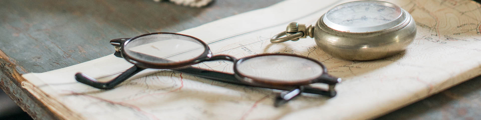 Une vieille paire de lunettes et une montre de poche sur une carte pliée des années 1940.