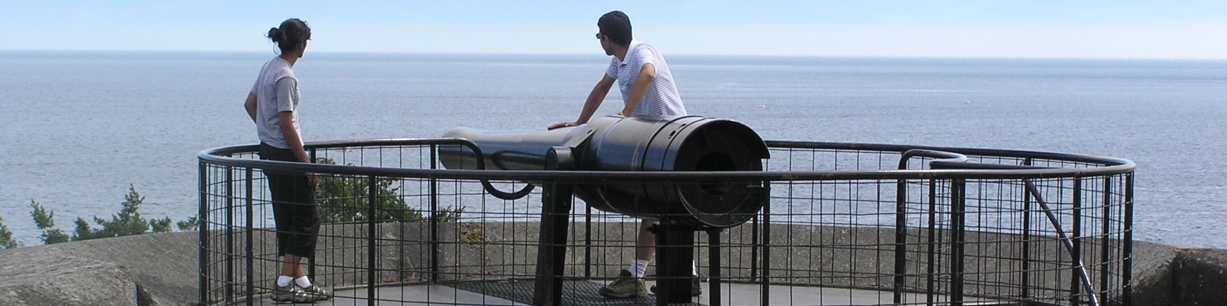 A couple standing by a large canon looks at the view