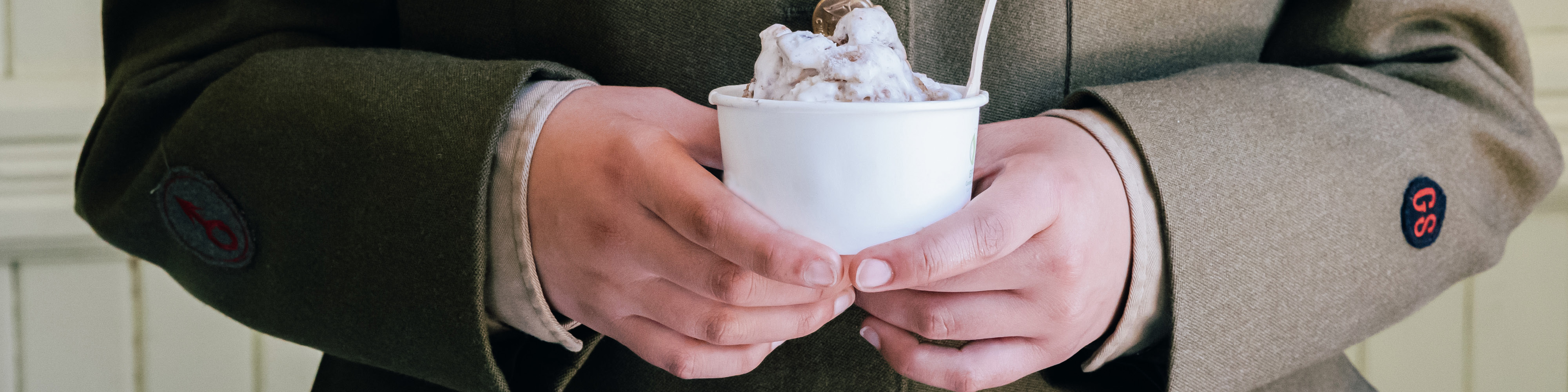 Hands holding a cup of ice cream.