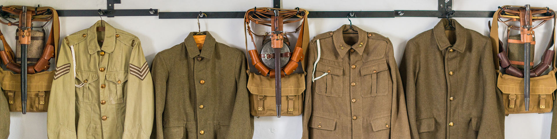 "Exposition présentée à la casemate mettant en valeur des pièces d’uniformes accrochées au mur.