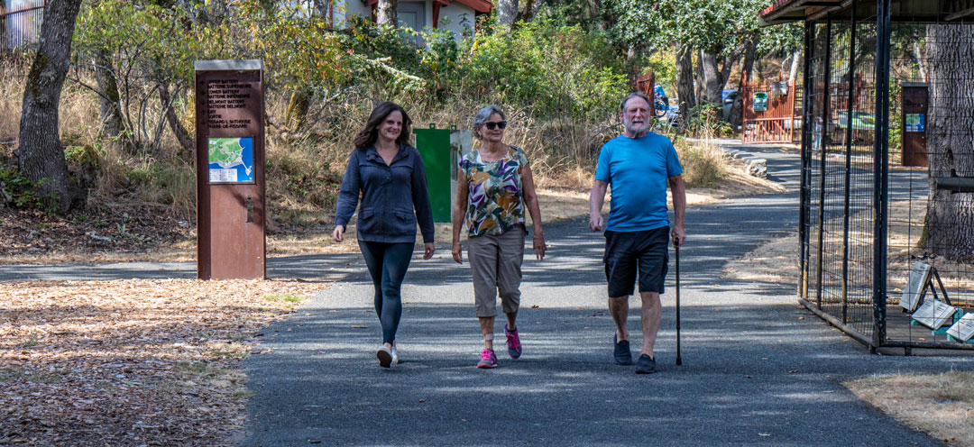 Three adults, one with a cane, walk down the main pathway.