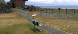 A bench located near a pathway leading to the Searchlight emplacement and the adjacent beach.