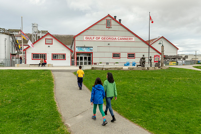 Family of three walking up path through Fisherman's Park towards the Cannery.