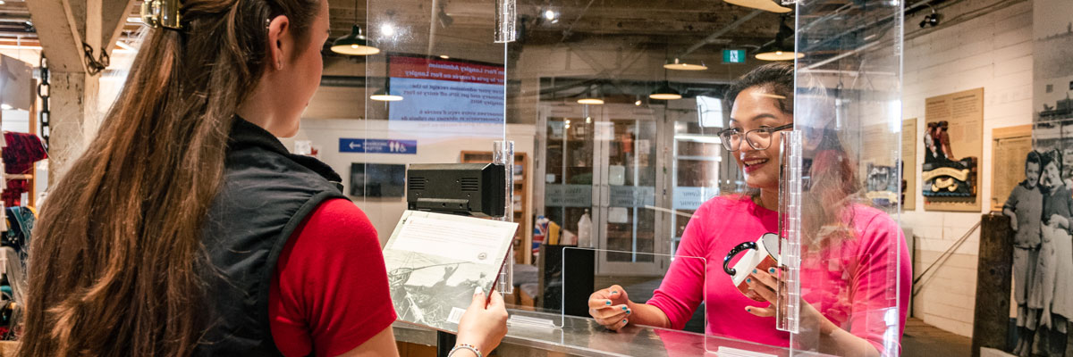 A Gulf of Georgia Cannery National Historic Site staff member greets a visitor at the front reception desk.