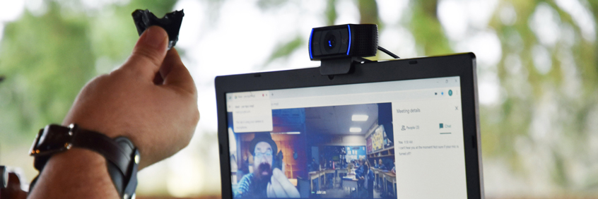 Un guide-interprète tenant un morceau de pierre à une webcam pendant une programme scolaire virtuelle