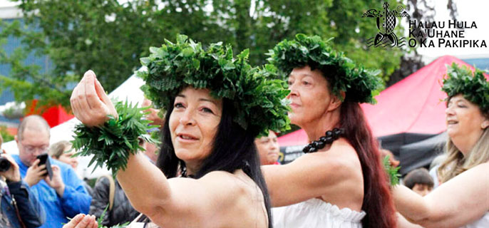 Un groupe de danseuses portant des robes hawaïennes traditionnelles dansent joyeusement ensemble.