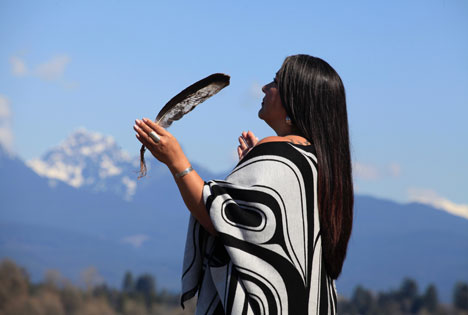 An indigenous person us a feather in hand look at the sky