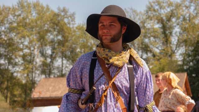 A costumed interpreter dressed in traditional 19th-century fur trade attire.