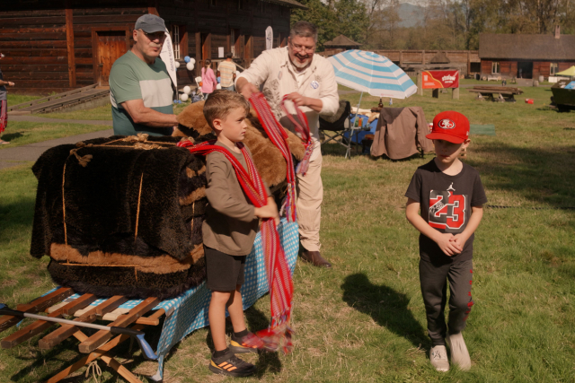 Two adults and two children playing a Métis traditional game with a ceinture fléchée.