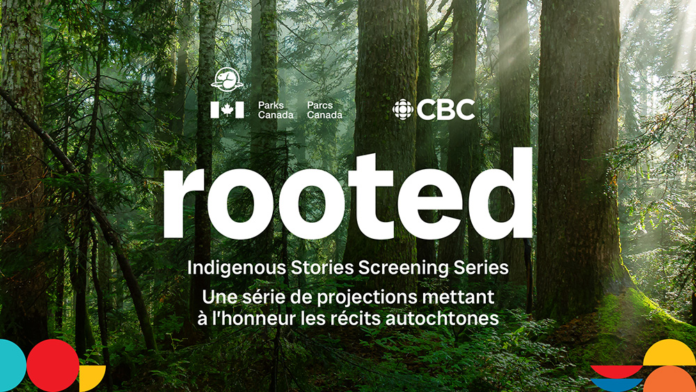 Une scène forestière verdoyante où de grands arbres laissent filtrer la lumière à travers leur couvert. Un texte superposé affiche le mot « rooted » en grandes lettres blanches, suivi, en plus petits caractères, de la mention « Série de projections mettant à l’honneur les récits autochtones ». Les logos de Parcs Canada et de la chaîne CBC figurent dans la partie supérieure.