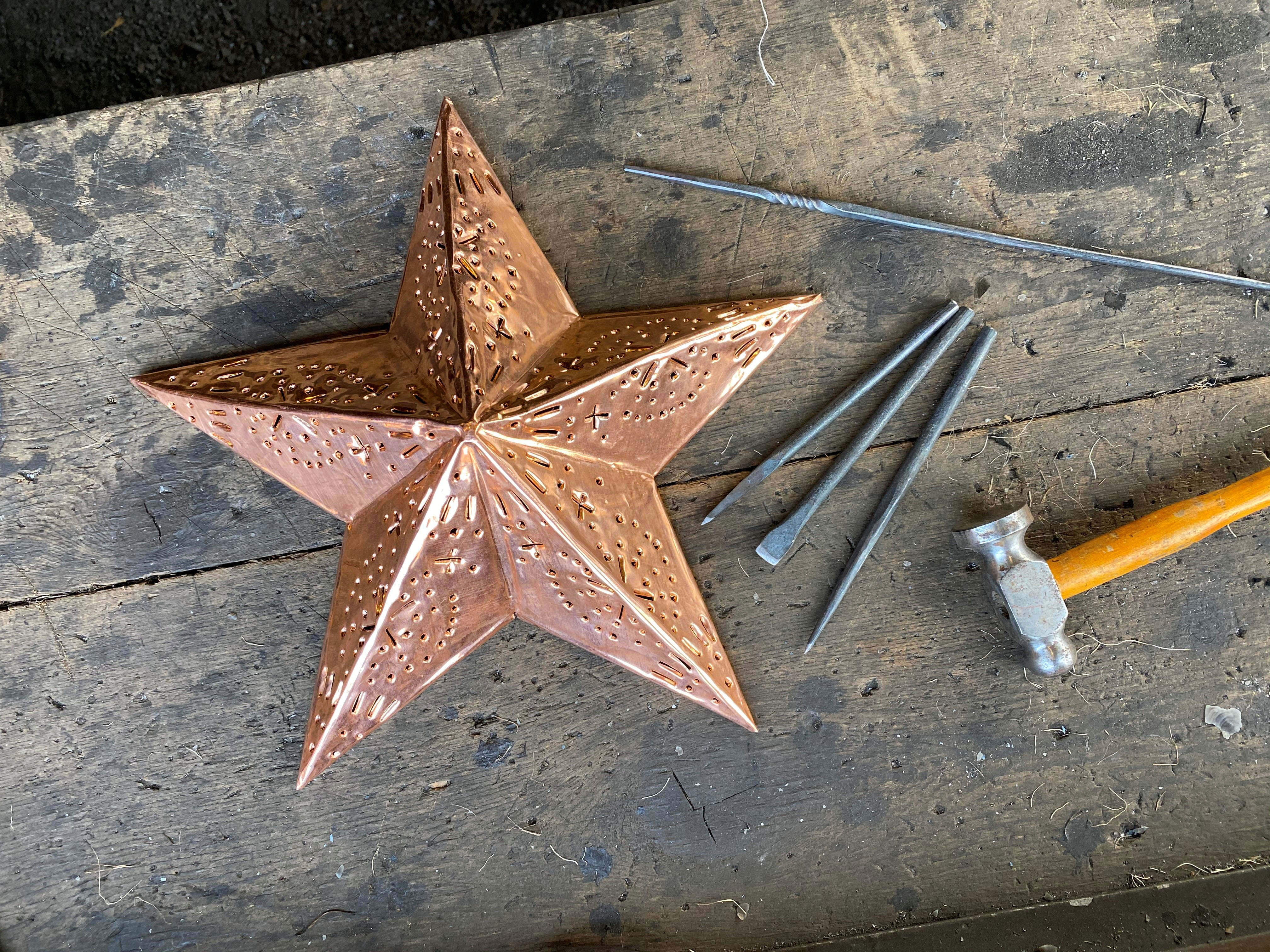 Une étoile en cuivre sur une table avec des clous et un marteau