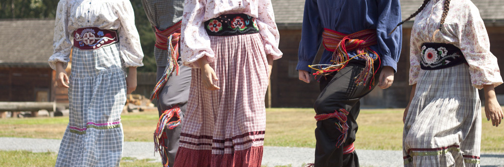 Danseurs métis pratiquant la gigue en écharpe et en costume traditionnel décoré de perles.