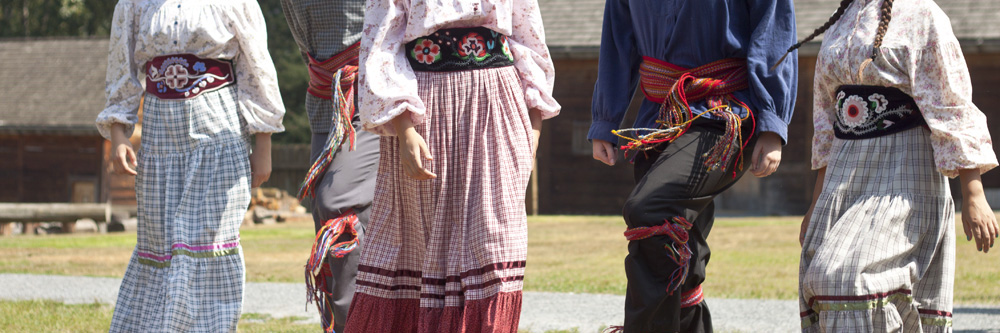 Métis dancers jigging in sashes and beaded regalia.