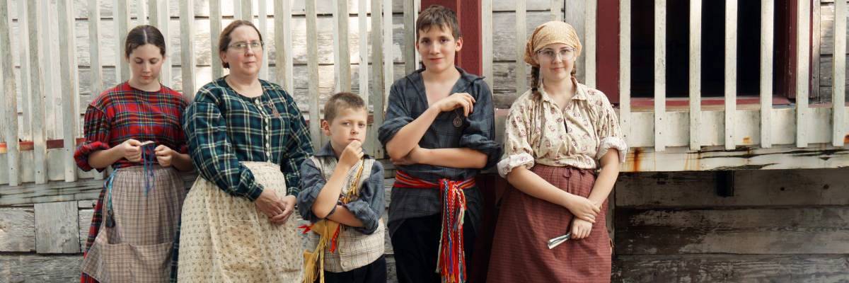 A mother and her four children dressed in 19th-century attire.