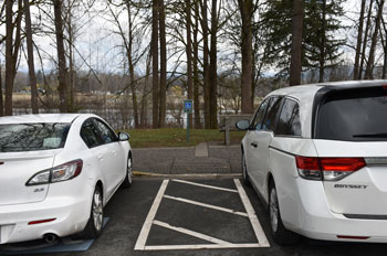 Deux voitures sont stationnées dans des places de stationnement accessibles. Une allée d’accès se trouve entre les véhicules.