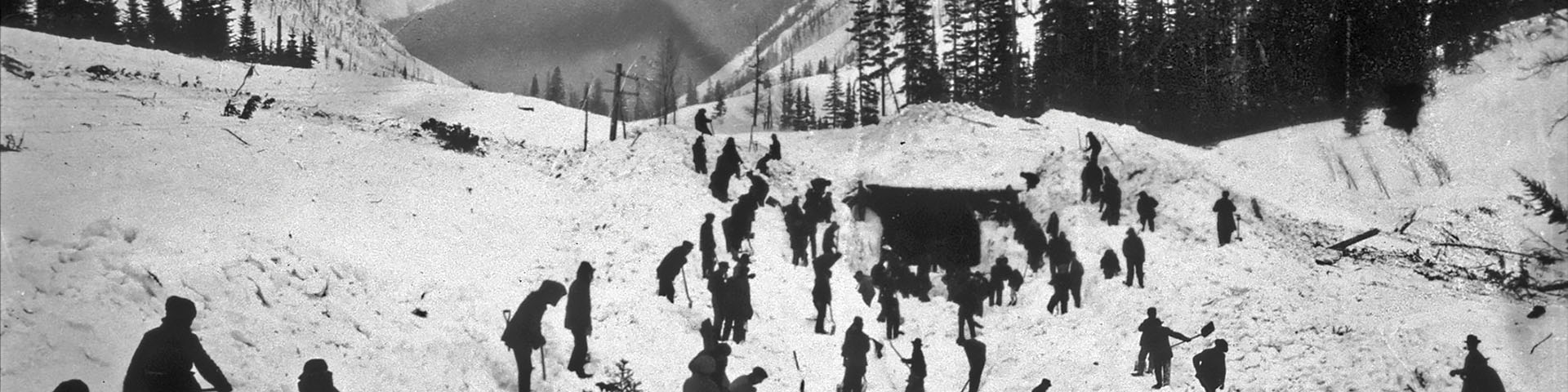 Old black and white photo of 30 people diffing the railing out from an avalanche