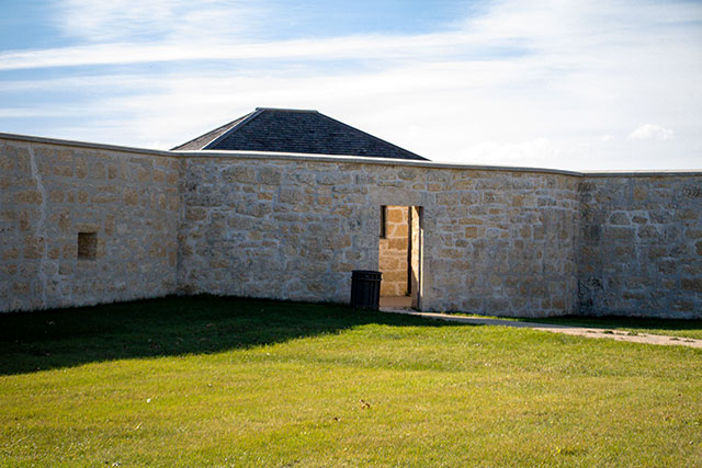 A gravel path leads to an entrance in a stone bastion.