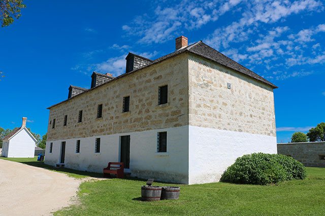 A light-coloured three-story building of partially white and partially beige stone.