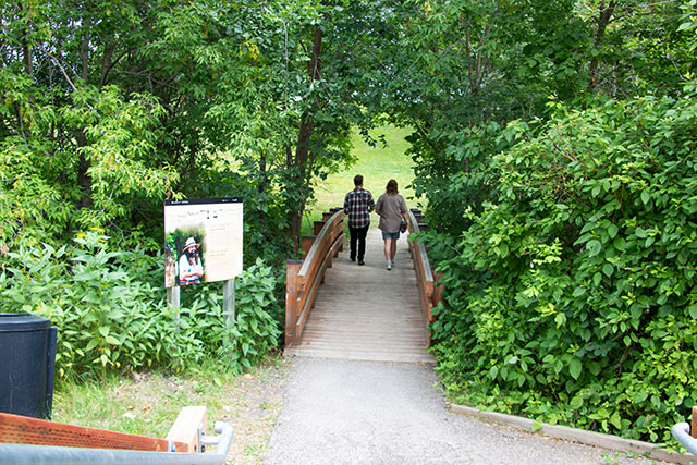 Two visitors with their backs to the camera walk across a footbridge.