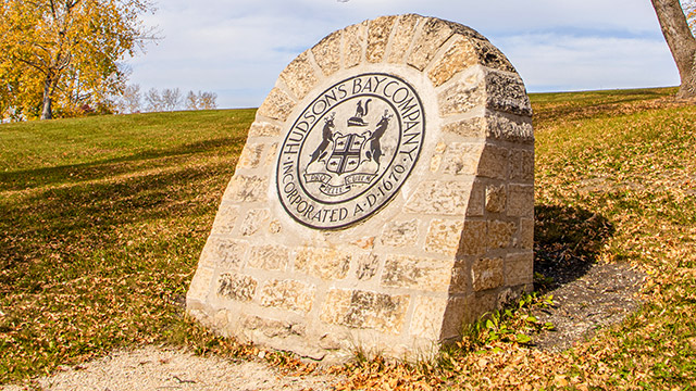 Un gros monument en briques, arqué au sommet, sur lequel est gravé le logo de la Compagnie de la Baie d’Hudson, se dresse sur une colline.