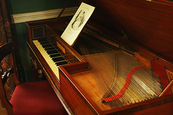 Three-quarter top view of the pianoforte with the lid open and strings exposed, from the right side.
