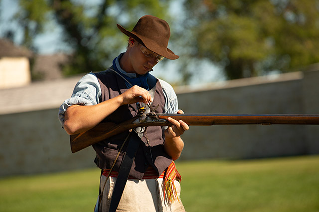 A man prepares to fire a historic rifle. 