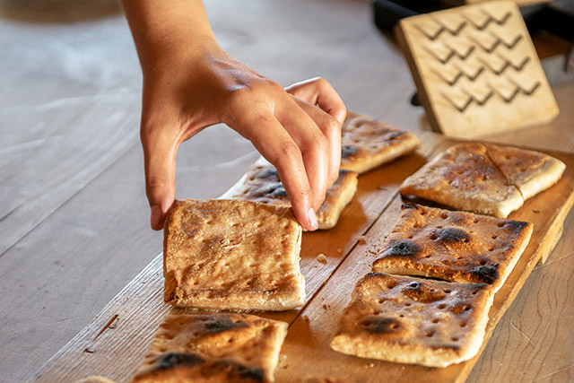A close-up of a hand tilting a thick square biscuit toward the camera.