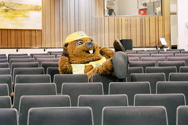 Parks Canada beaver mascot Parka leans back in a seat in a theatre.